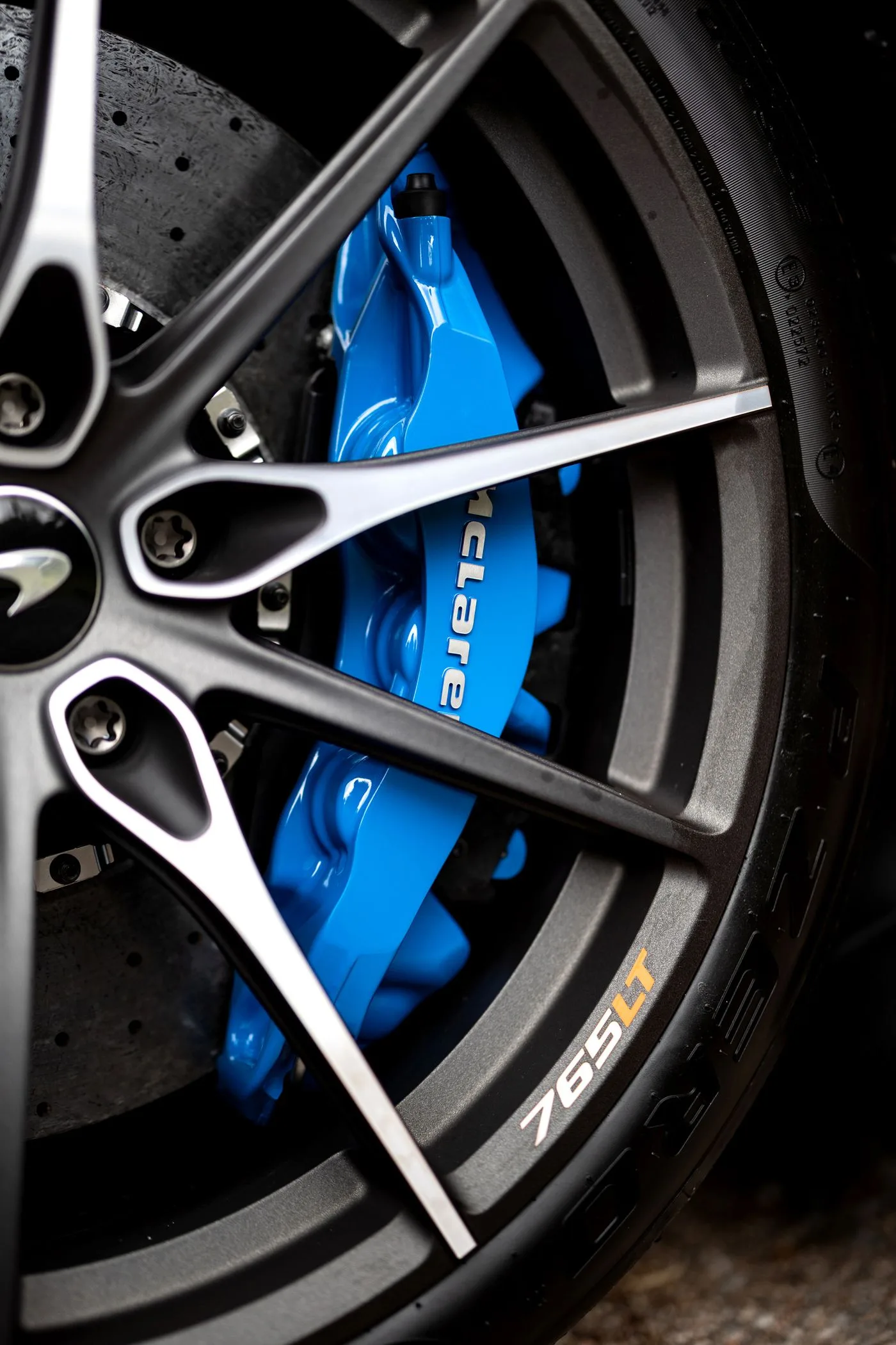 Blue painted brake caliper behind a black alloy wheel