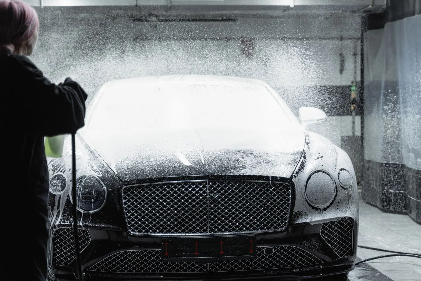 A black Bentley being foam-washed, viewed from the front
